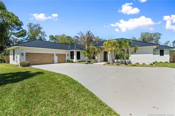 a front view of a house with a yard and potted plants