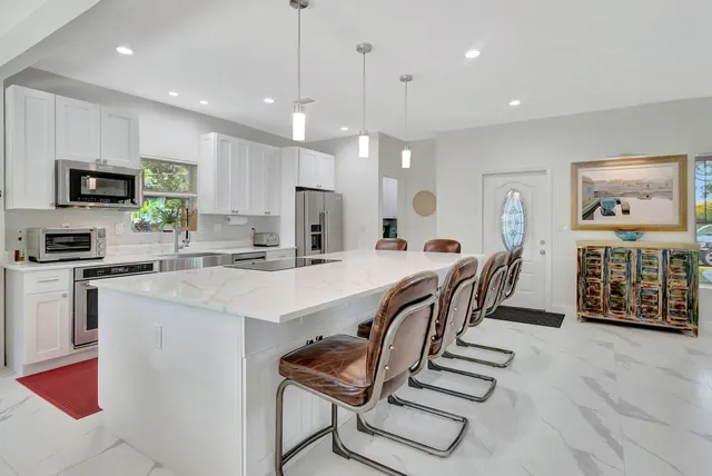 a kitchen with stainless steel appliances kitchen island granite countertop a refrigerator a stove a microwave oven a sink with island and chairs