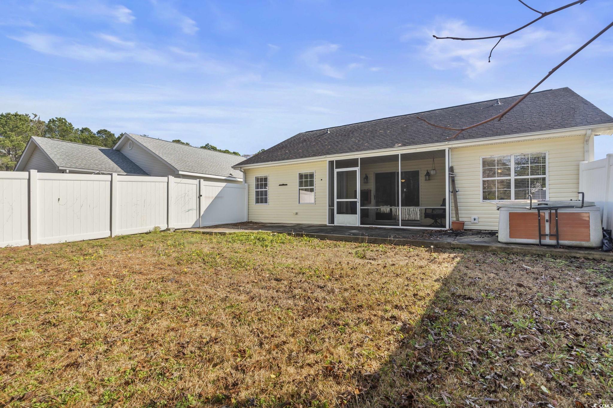 8010 Cone Court Murrells Inlet, SC 29576 - Photo 22 of 29 Rear view of property featuring a fenced backyard, a sunroom, roof with shingles, a hot tub, and a patio