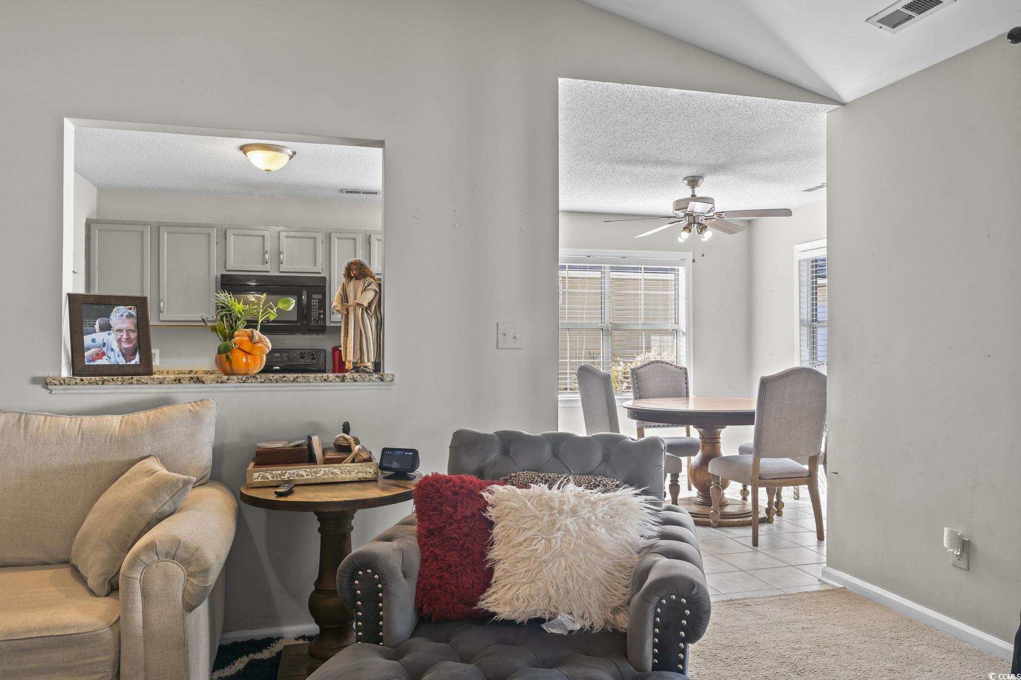 8010 Cone Court Murrells Inlet, SC 29576 - Photo 9 of 29 Living area with a textured ceiling, light tile patterned floors, vaulted ceiling, and a ceiling fan