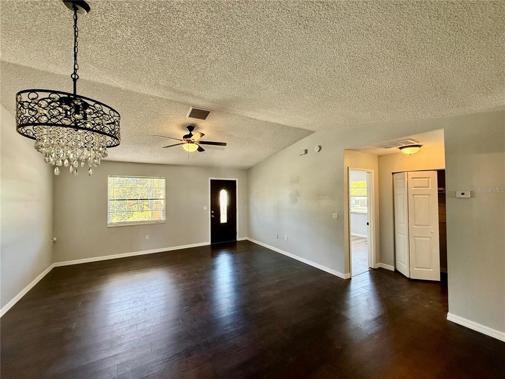 8124 Cormel Street, Unit 8126 Port Richey, FL 34668 - Photo 2 of 13 an empty room with wooden floor chandelier and windows