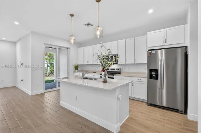 a kitchen with kitchen island white cabinets and stainless steel appliances