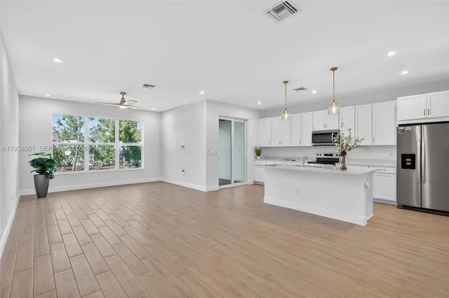 a view of kitchen with stainless steel appliances refrigerator stove microwave and cabinets