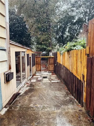 a view of backyard with large trees and wooden fence