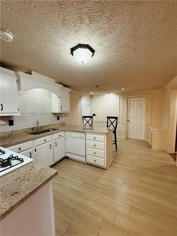 a large white kitchen with kitchen island a sink stainless steel appliances and cabinets