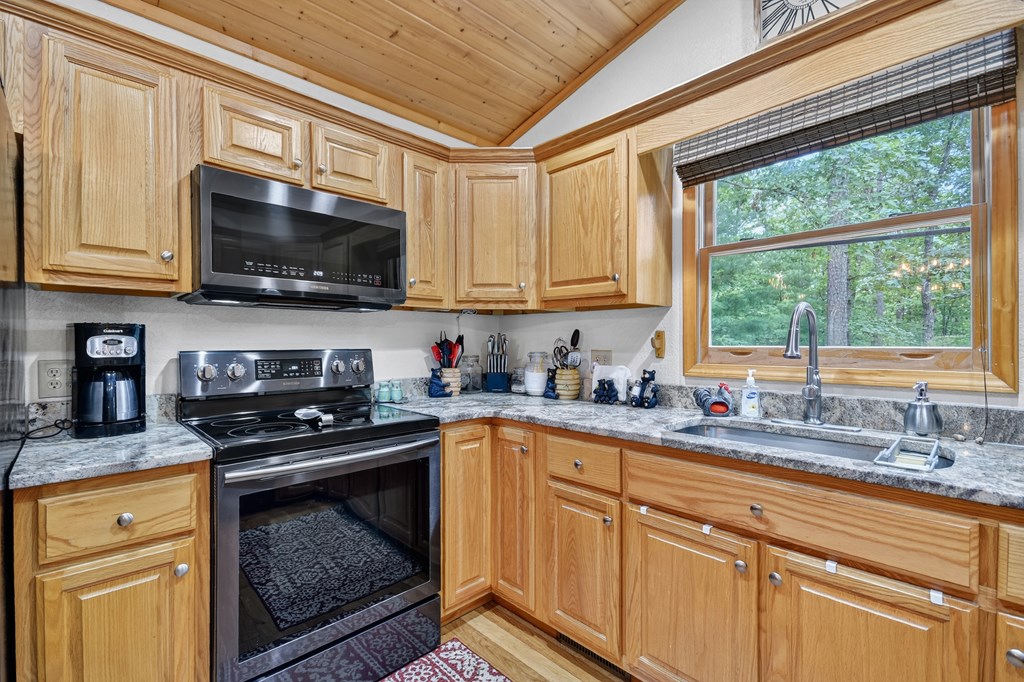 1044 Boulder Crk Road Murphy, NC 28906 - Photo 26 of 38 a kitchen with stainless steel appliances granite countertop a sink a stove a microwave and wooden cabinets