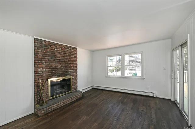 an empty room with wooden floor fireplace and windows