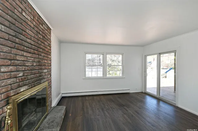 a view of an empty room with wooden floor fridge and a window