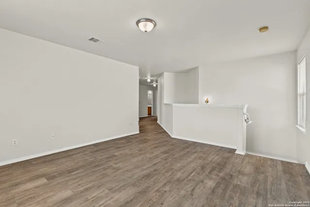 a view of an empty room with wooden floor and cabinet