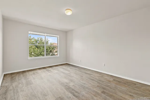 a view of an empty room with wooden floor and a window