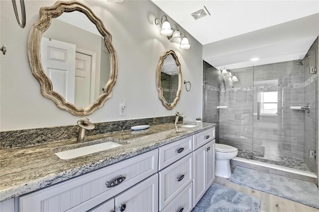 2855 North Rivers Edge Boulevard, Unit 213 Crystal River, FL 34429 - Photo 25 of 62 a bathroom with a granite countertop toilet a sink and a mirror