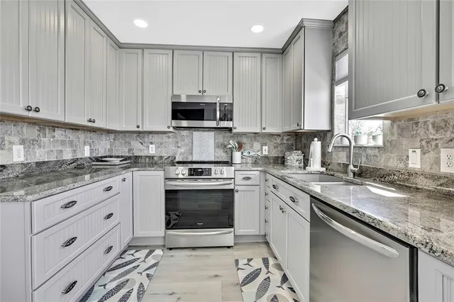 a kitchen with stainless steel appliances granite countertop a refrigerator stove and white cabinets