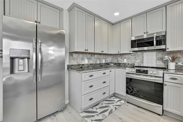a kitchen with granite countertop white cabinets and white stainless steel appliances