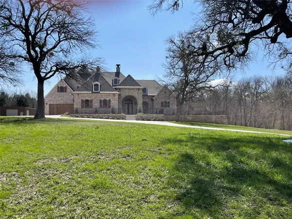 a front view of a house with garden and trees