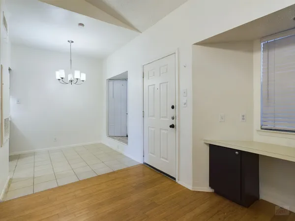 a view of an empty room with window and chandelier fan