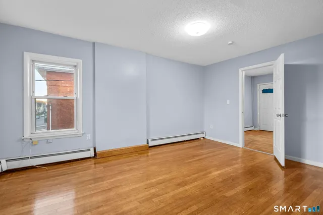 a view of an empty room with wooden floor and a window
