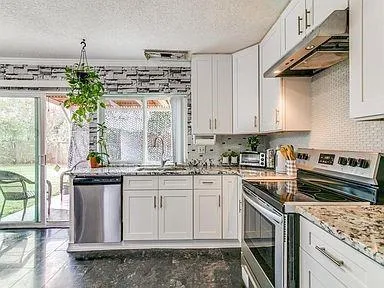 a kitchen with stainless steel appliances granite countertop a stove a sink and a microwave