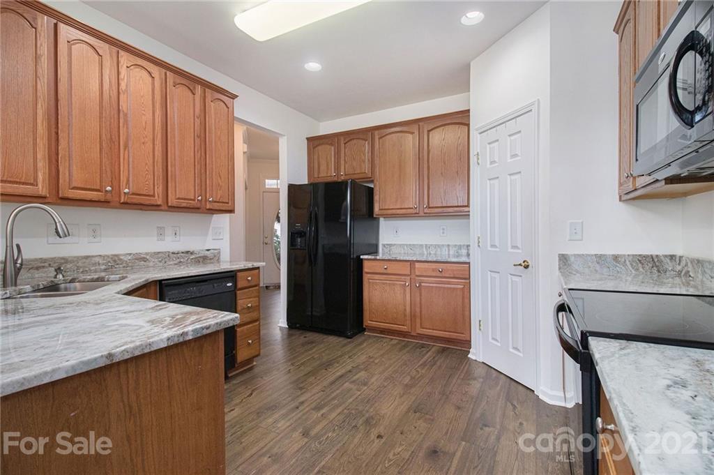 287 Garnet Court Fort Mill, SC 29708 - Photo 5 of 30 a kitchen with granite countertop a refrigerator a sink dishwasher and wooden cabinets with wooden floor