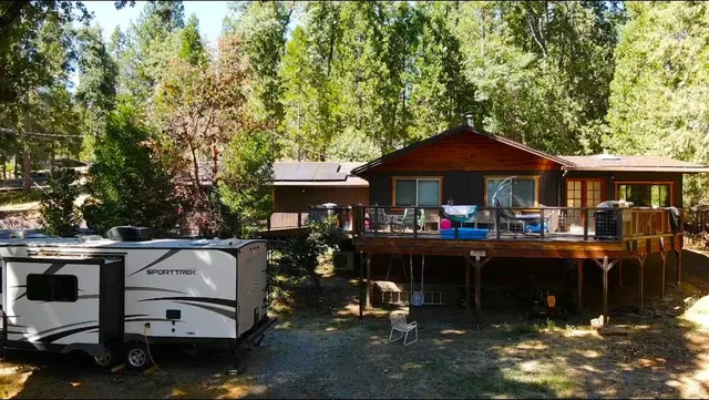 a view of a patio with table and chairs under an umbrella with a barbeque