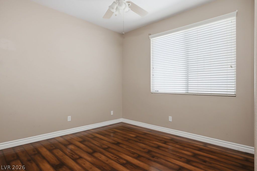 9712 North Running Rabbit Street Las Vegas, NV 89143 - Photo 20 of 42 Rich wood flooring provides a warm foundation in this inviting bedroom, illuminated by a window with privacy blinds.