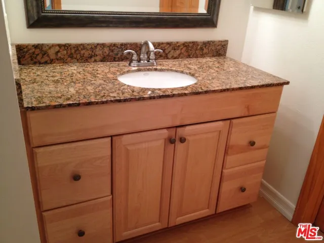 a bathroom with a granite countertop sink and a mirror