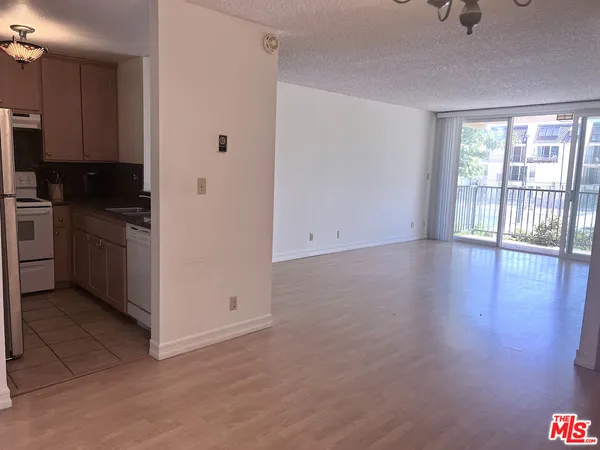 a view of a kitchen with wooden floor electronic appliances and windows