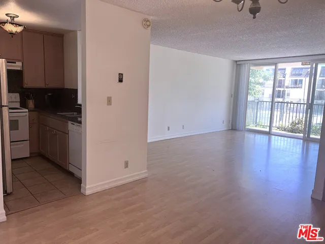 a view of a kitchen with wooden floor electronic appliances and windows