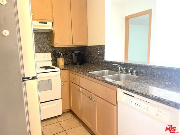 a kitchen with granite countertop a sink stove and cabinets