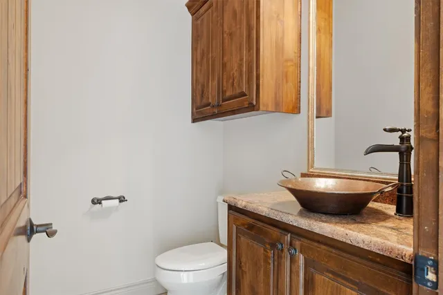a bathroom with a granite countertop toilet and a sink