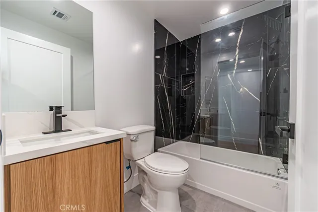 a bathroom with a granite countertop sink toilet and shower