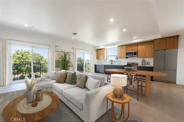 a living room with kitchen couches kitchen view and a large window
