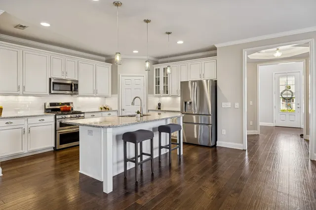 a kitchen with stainless steel appliances granite countertop a refrigerator stove microwave and white cabinets