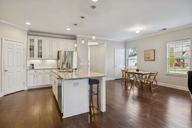 a kitchen with white cabinets and chairs