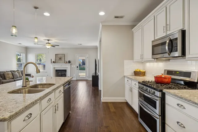 a kitchen with stainless steel appliances granite countertop a sink dishwasher a stove and a microwave oven with cabinets