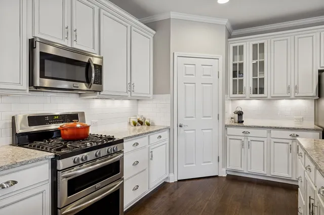 a kitchen with stainless steel appliances granite countertop white cabinets and a stove a oven with wooden floor