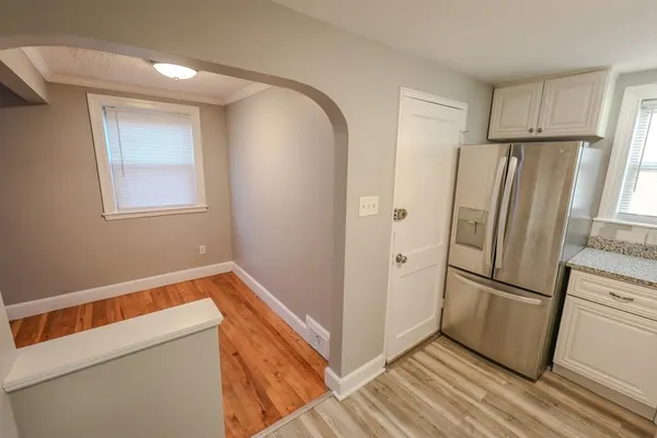 a view of a kitchen with refrigerator and wooden floor