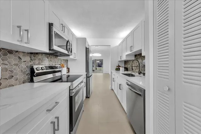a kitchen with white cabinets and sink