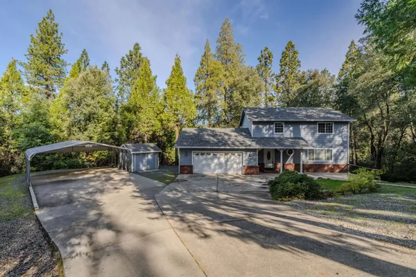 a view of a house next to a yard with plants and trees