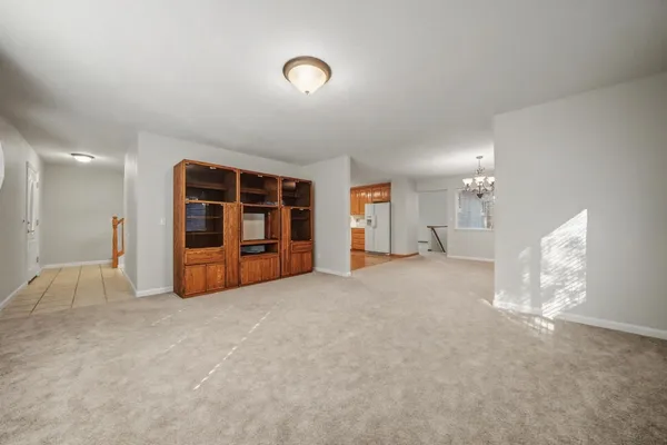 a view of an empty room with a window and kitchen