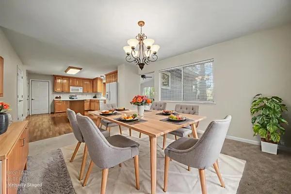 a view of a dining room with furniture a chandelier and a window