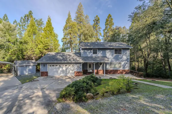 a front view of a house with a garden and trees