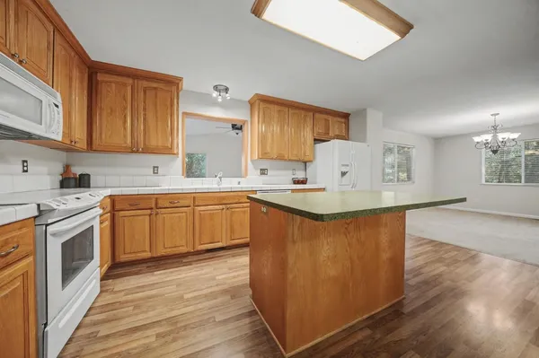 a kitchen with stainless steel appliances granite countertop a stove a sink dishwasher and a refrigerator with wooden floor