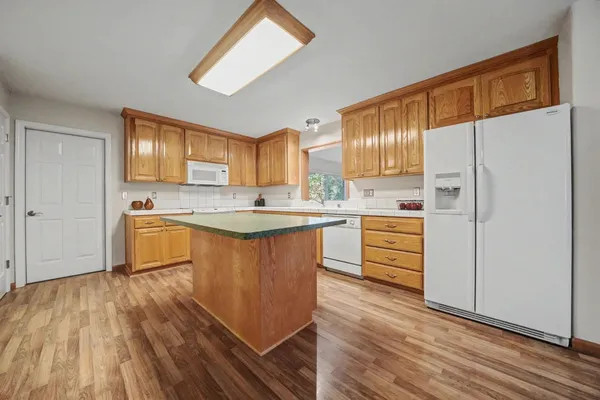 a kitchen with stainless steel appliances granite countertop a refrigerator a sink dishwasher a stove with wooden floor and cabinets