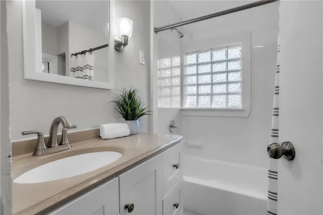 a bathroom with a granite countertop sink a mirror a potted plant and a shower