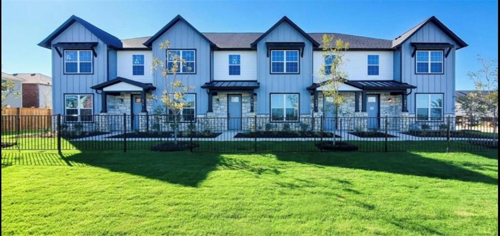 1658 Palladio Loop Princeton, TX 75407 - Photo 17 of 18 Modern townhome exterior featuring vertical siding, stone accents, black window trim, and a manicured lawn