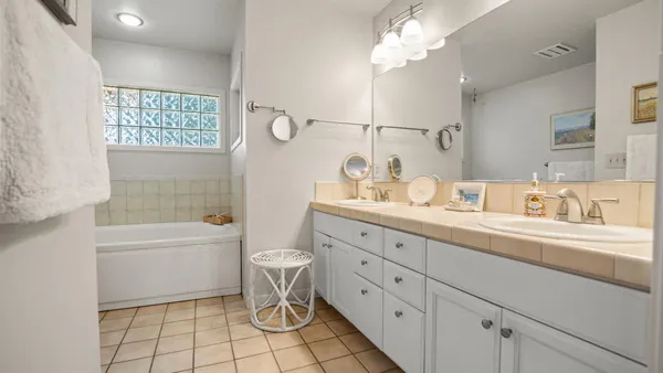a spacious bathroom with a granite countertop sink a toilet a mirror a vanity a bathtub and shower