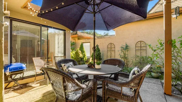 a view of an outdoor dining space with a table and chairs under an umbrella