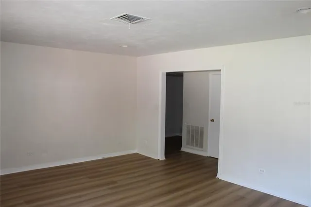 a view of an empty room with wooden floor and closet