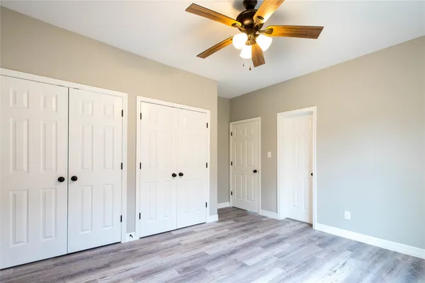 a view of an empty room with window and a chandelier fan
