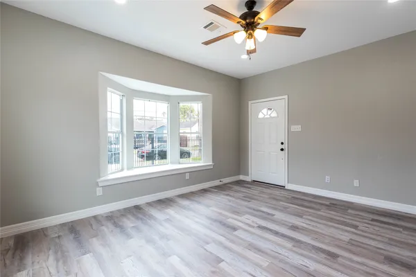 an empty room with wooden floor and a ceiling fan